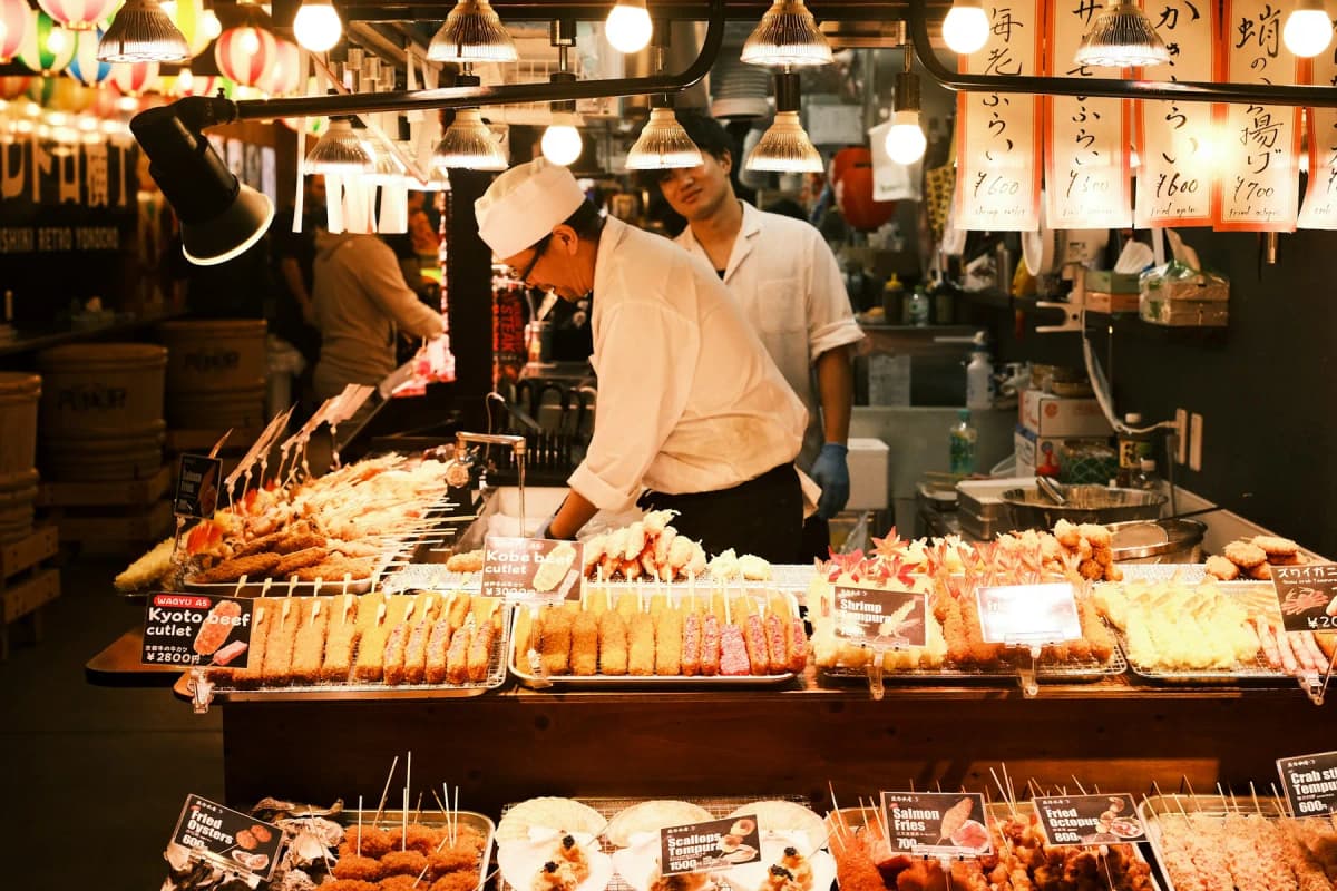 A vendor arranging grilled skewers at a food stall in Nishiki Market in Kyoto