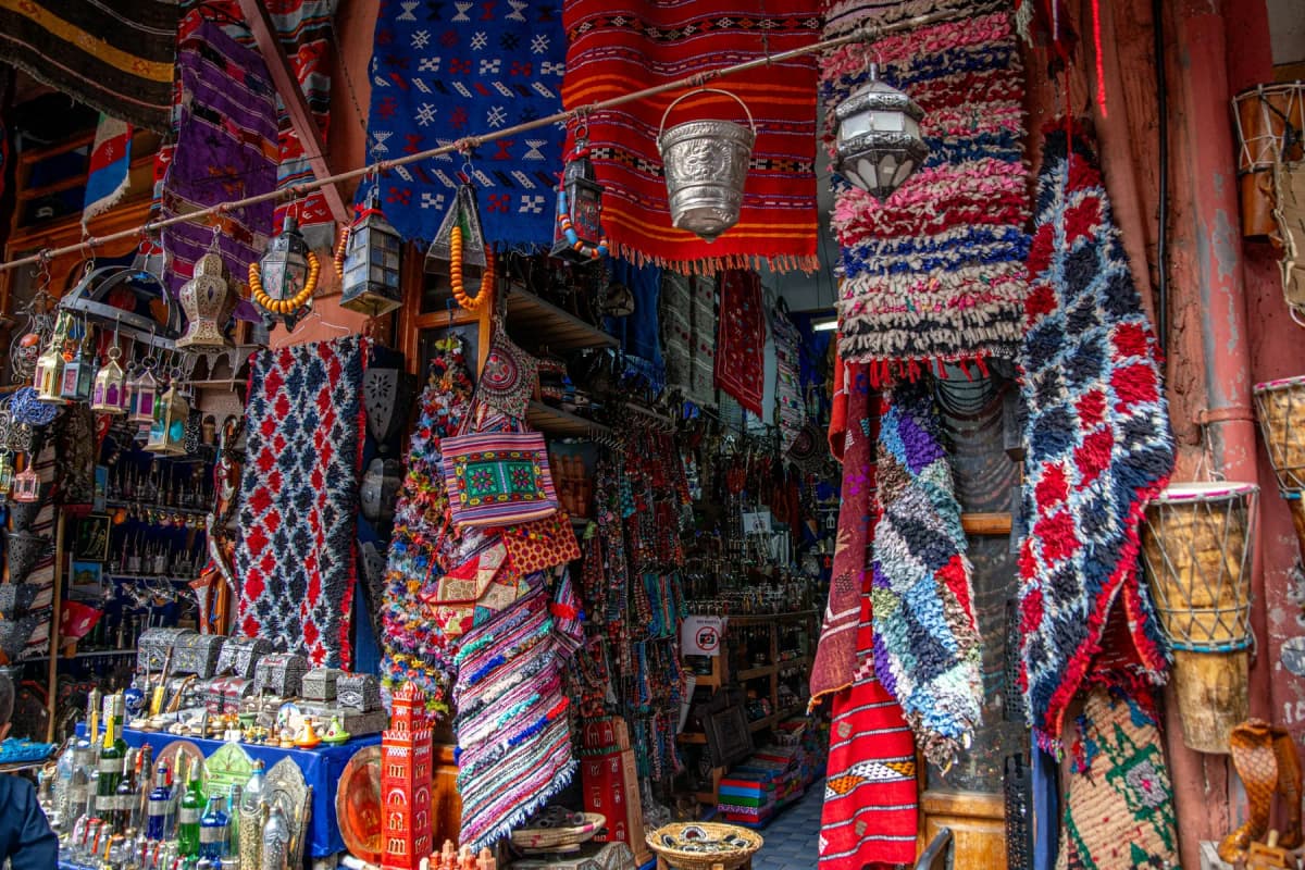 Colourful carpets and woven textiles stacked and hanging at a stall in the Marrakech souks
