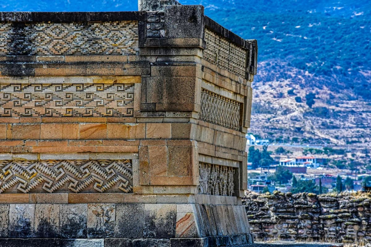 Geometric stone fretwork on a Zapotec building at Mitla, with hills and the town behind