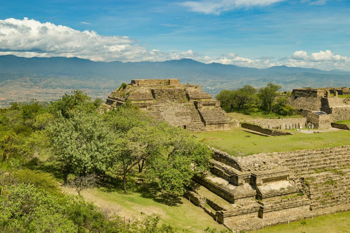 The terraced platforms of Monte Albán surrounded by trees, with the valley and mountains beyond