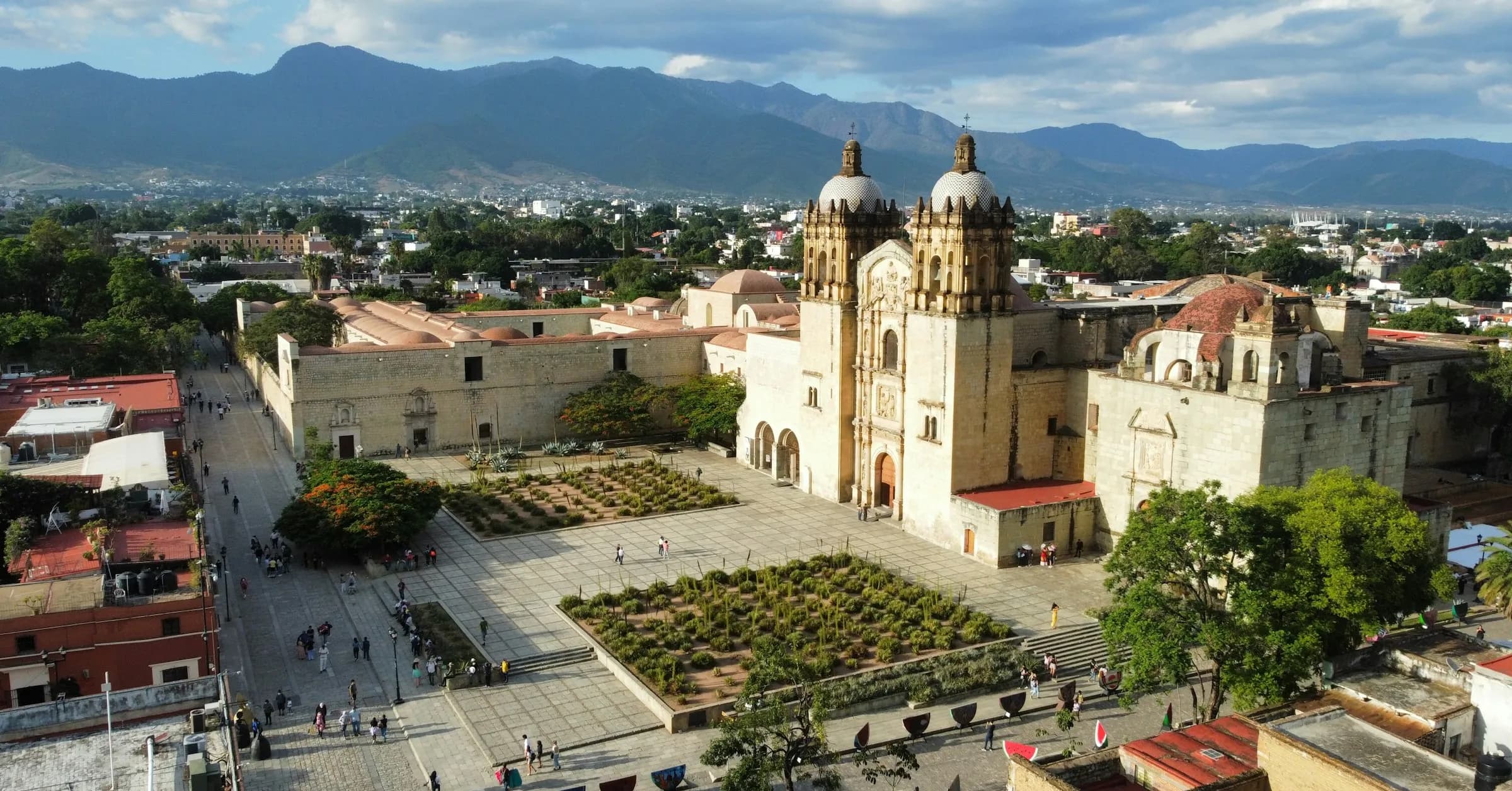 Things to do in Oaxaca: an aerial view of a domed colonial church and plaza in Oaxaca City with mountains behind
