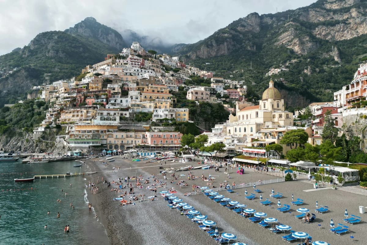 Spiaggia Grande beach in Positano with rows of sunbeds, the church dome and houses on the hillside behind