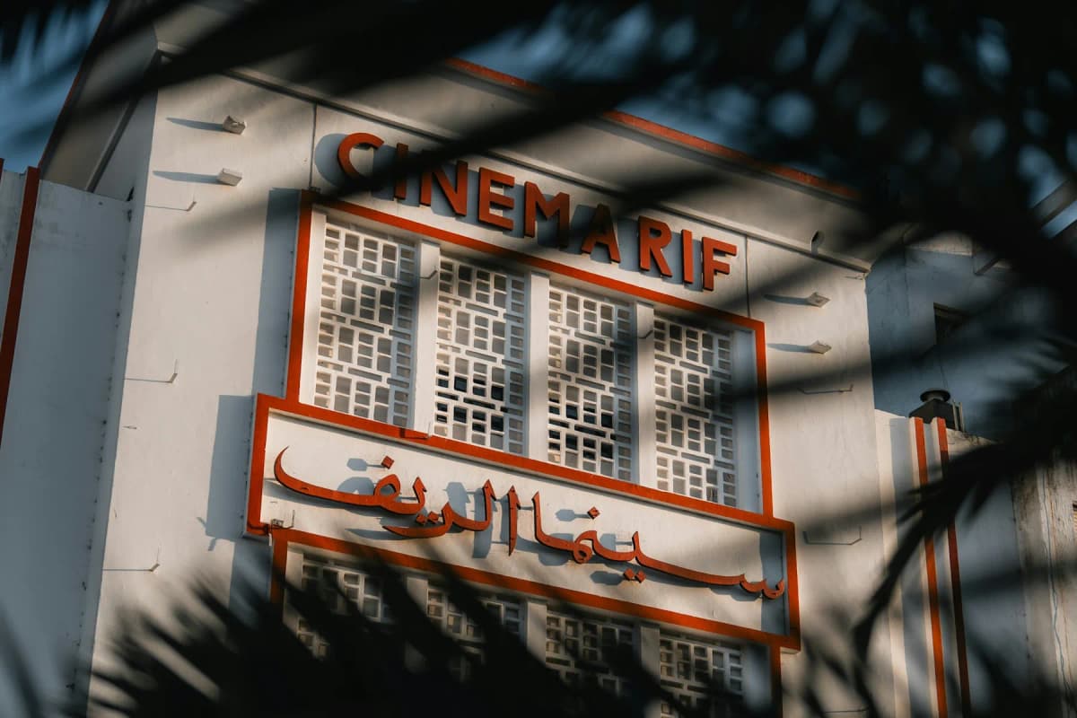 The red and white Art Deco front of Cinema Rif on the Grand Socco in Tangier, seen through palm leaves