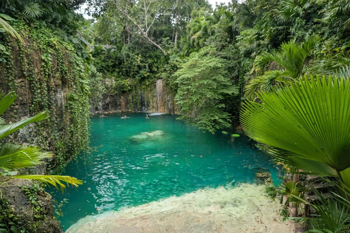 A cenote in the jungle near Tulum, with clear water below a rock wall