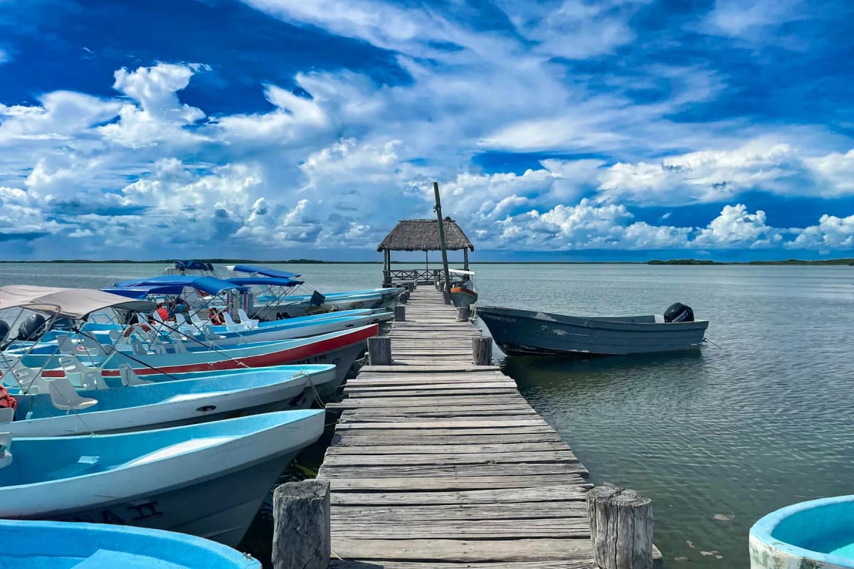 A wooden dock with small boats on a lagoon near Tulum