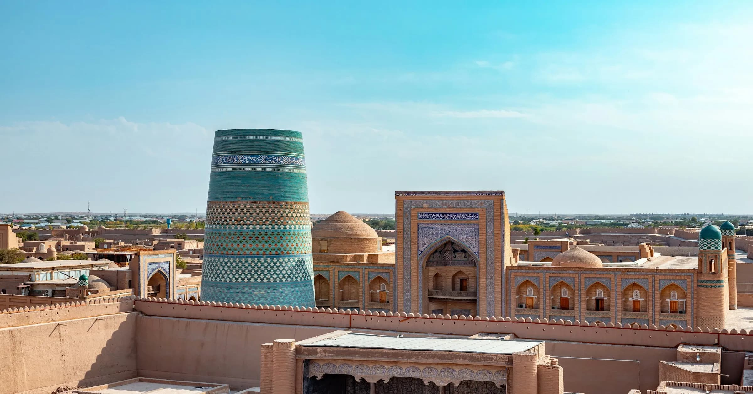 Things to do in Uzbekistan: the turquoise Kalta Minor minaret and mud-brick walls of Khiva's old town