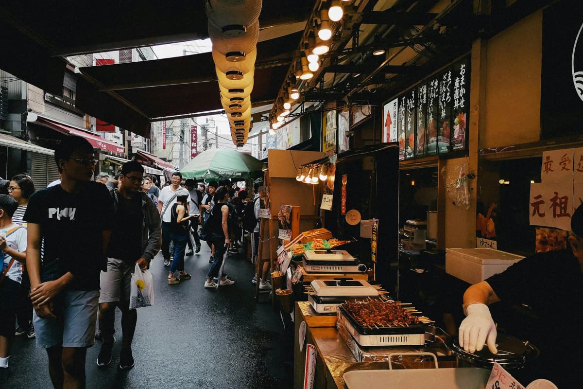 Shoppers walking past food stalls in Tsukiji Outer Market in Tokyo