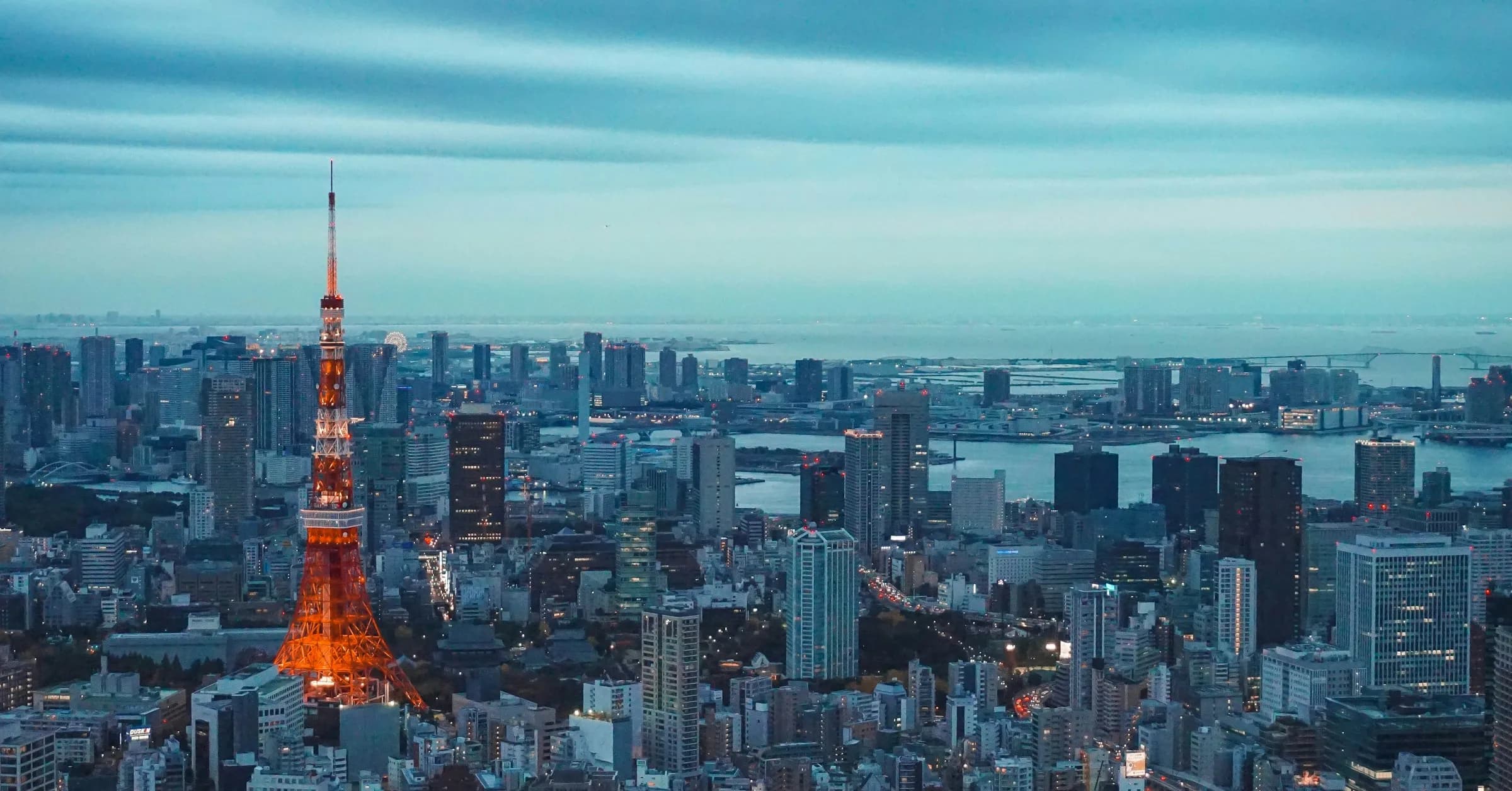 Tokyo itinerary: Tokyo Tower lit up above the city skyline and Tokyo Bay at dusk