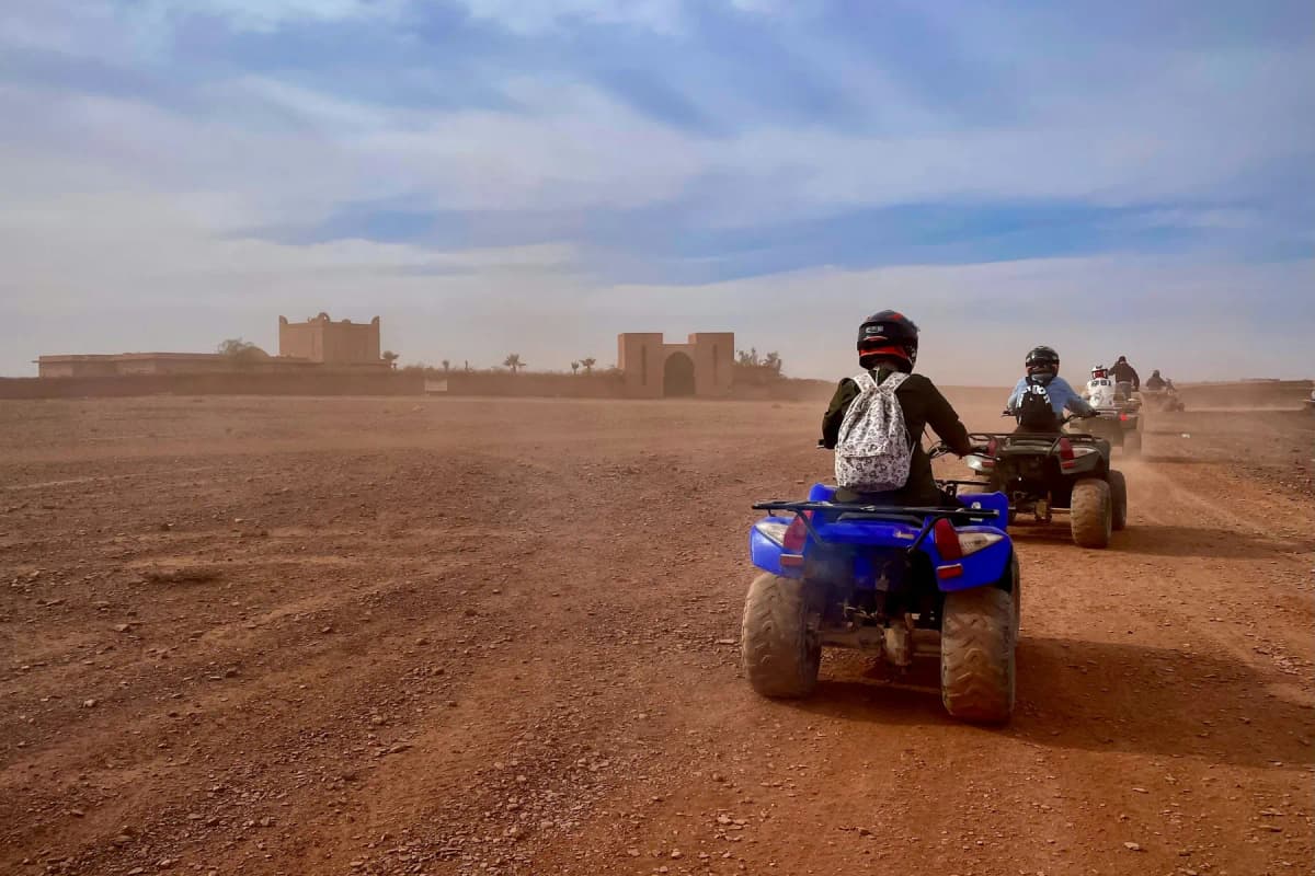 Tourists riding quad bikes across a red dirt plain in southern Morocco