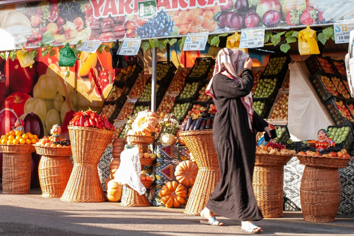 A woman walks past a colourful fruit stall at a bazaar in Uzbekistan