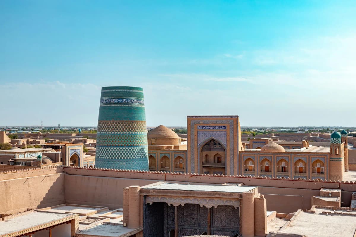 Uzbekistan itinerary: the turquoise Kalta Minor minaret above the mud-brick rooftops of Khiva's Itchan Kala