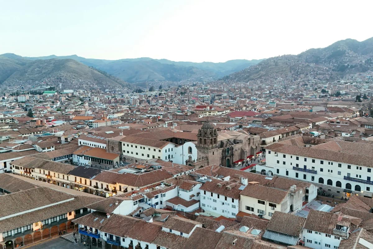 The red-tiled roofs of Cusco spreading across the valley, with mountains behind