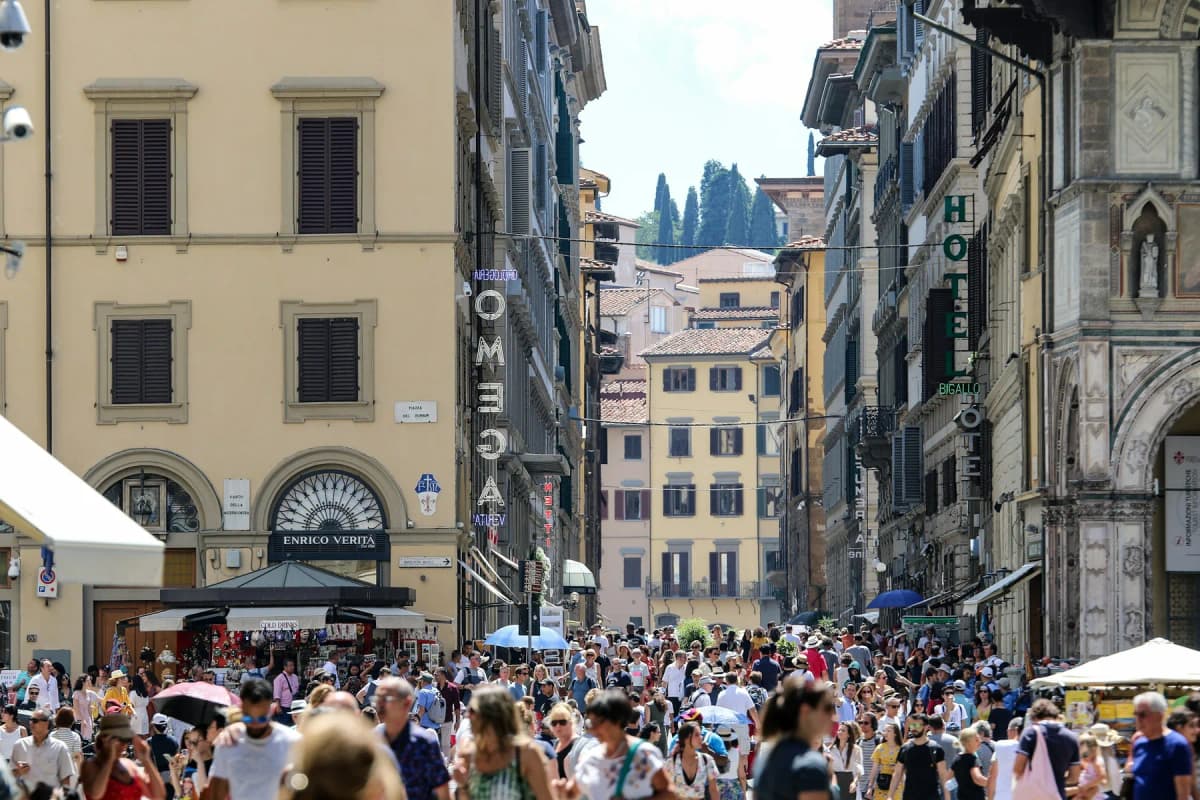 A crowded street in central Florence lined with tall historic buildings