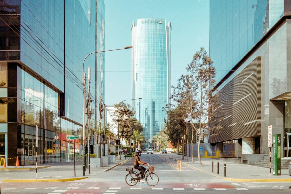 A cyclist on a quiet street between glass office towers in San Isidro