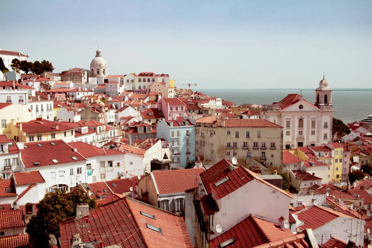 Alfama's terracotta rooftops and church domes above the Tagus river in Lisbon
