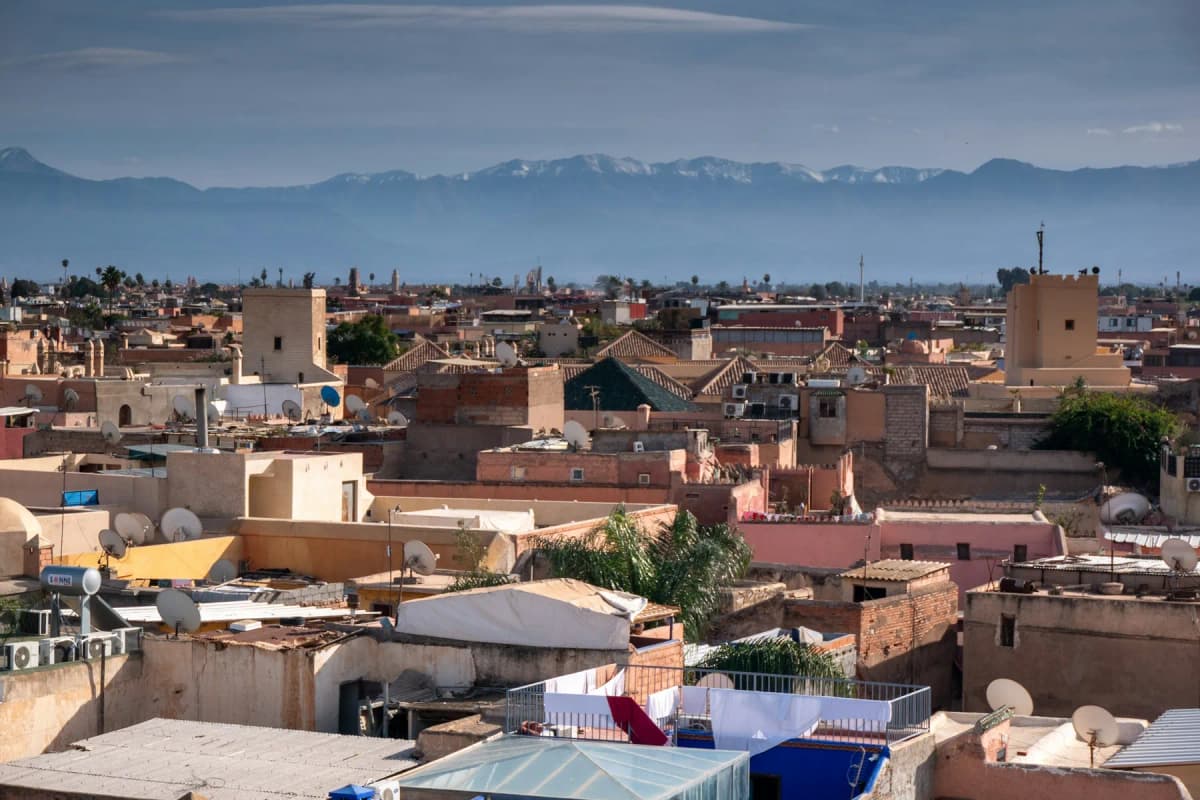 Flat rooftops of the Marrakech medina stretching towards the Atlas mountains on the horizon