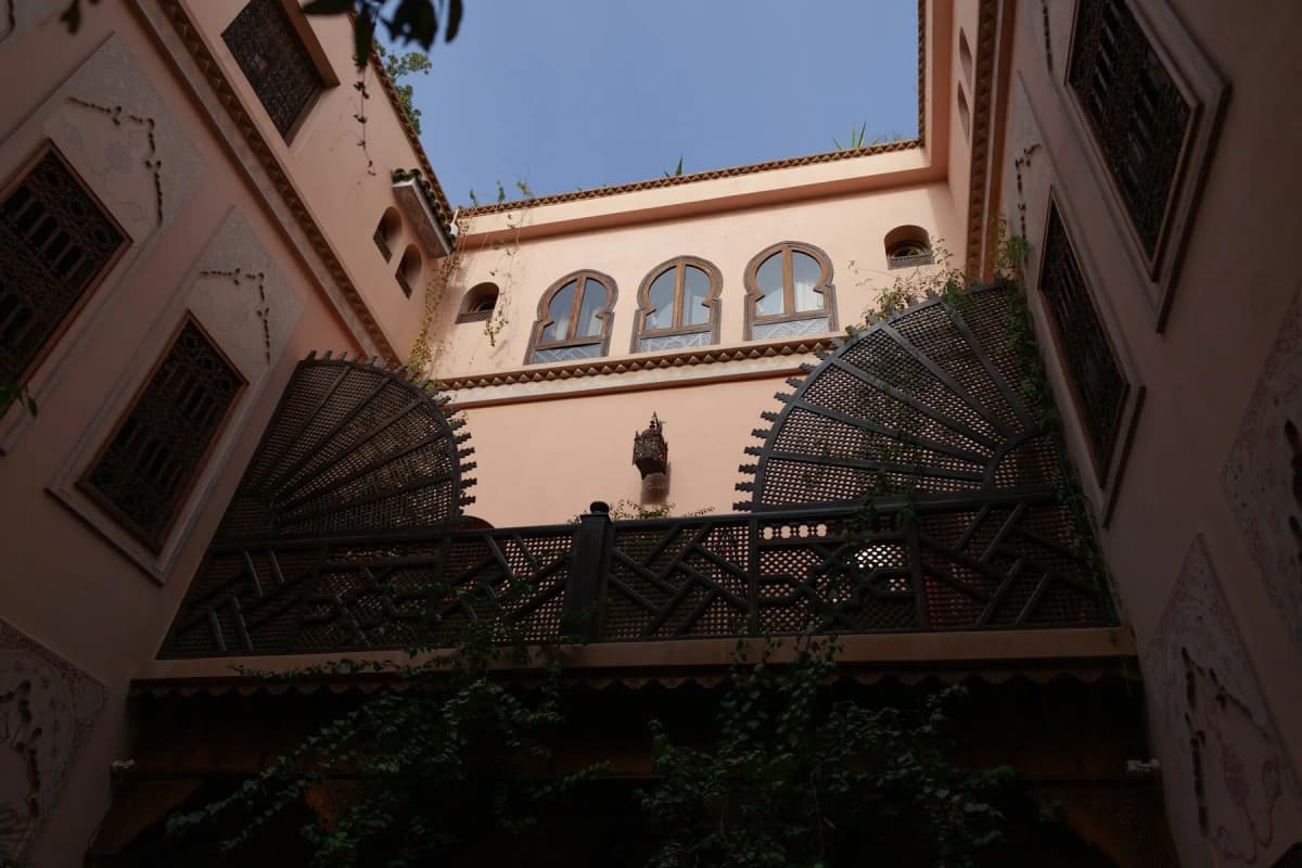 A carved wooden balcony and arched windows around the inner courtyard of a traditional Marrakech riad