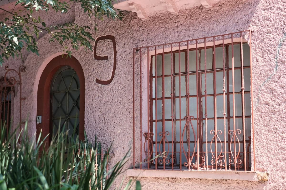 A pink building with ornate iron window grilles on a street in Condesa, Mexico City