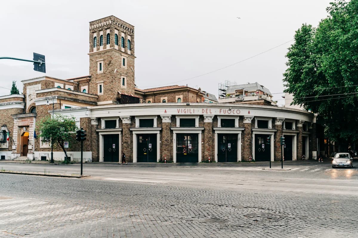 A low arcaded building and a brick bell tower on a quiet street in Rome's Testaccio district