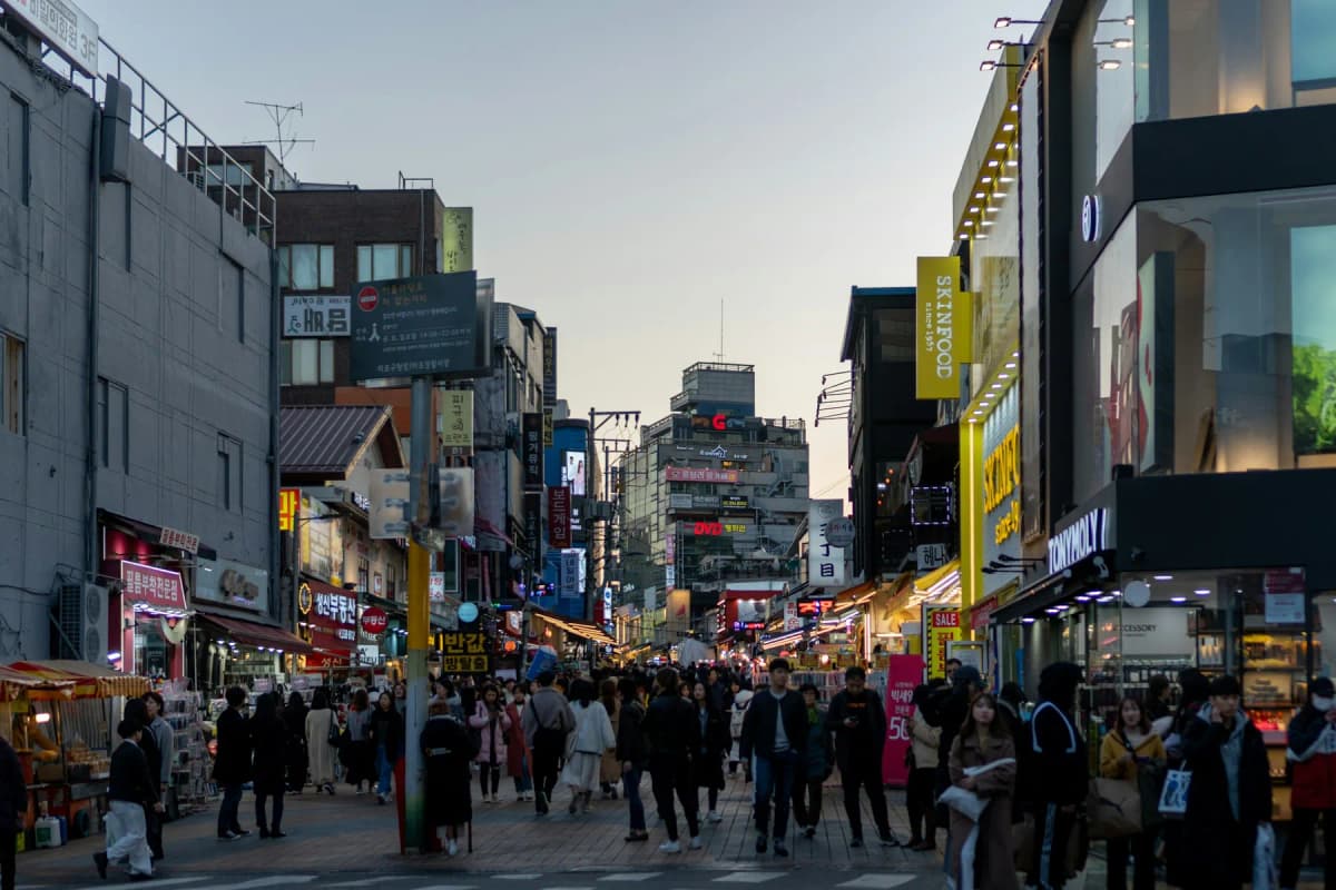 Shoppers walking along a busy street in Hongdae in the early evening