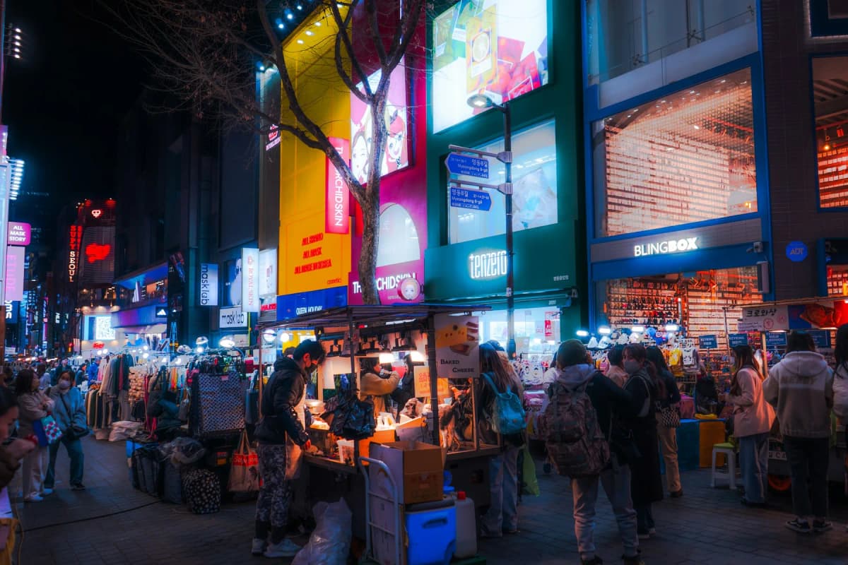 Crowds and street-food stalls on a neon-lit street in Myeongdong at night
