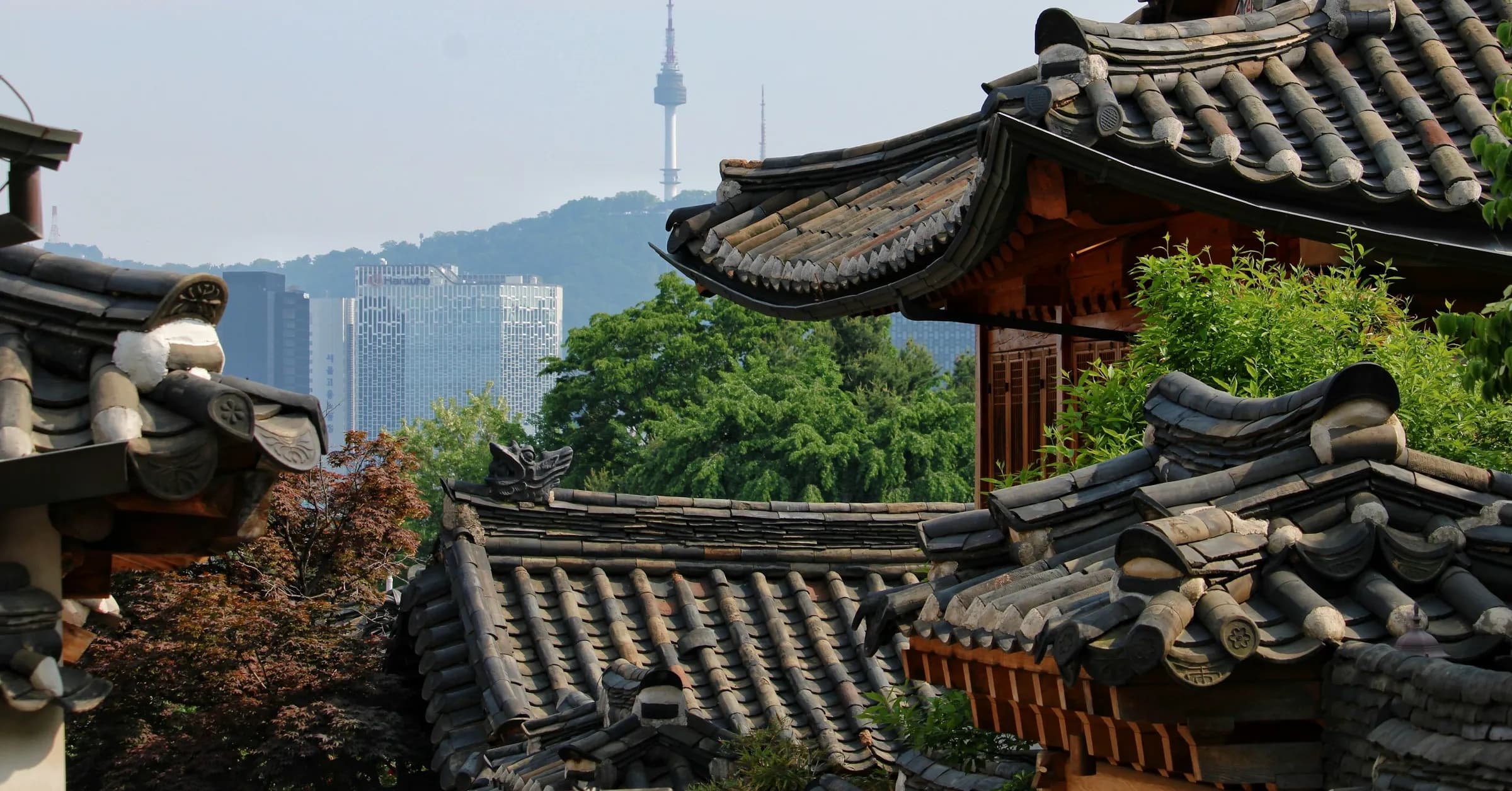 Where to stay in Seoul: the tiled roofs of Bukchon Hanok Village with N Seoul Tower on the hill behind