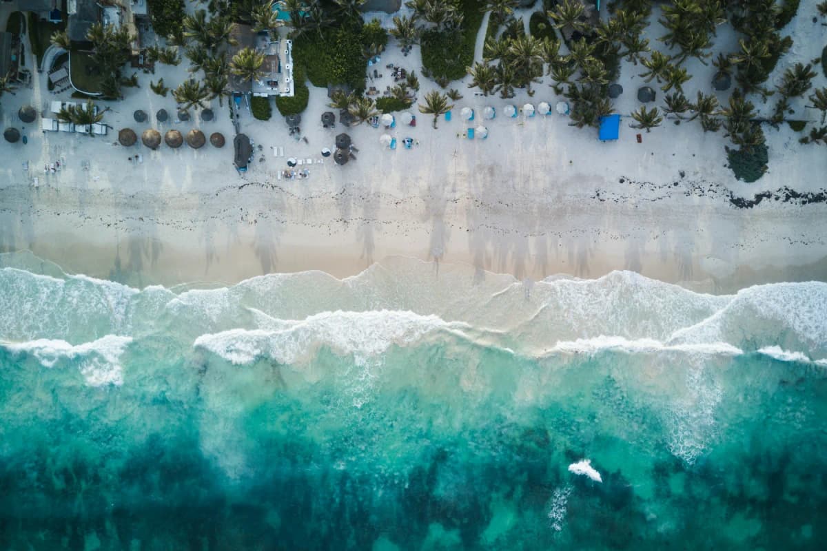 Beach umbrellas and loungers on the sand in Tulum's Hotel Zone, seen from above