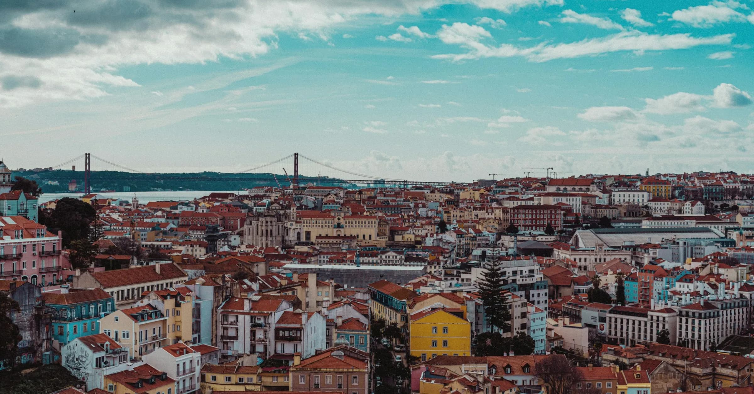 Lisbon itinerary: terracotta rooftops with the 25 de Abril Bridge and the Tagus behind