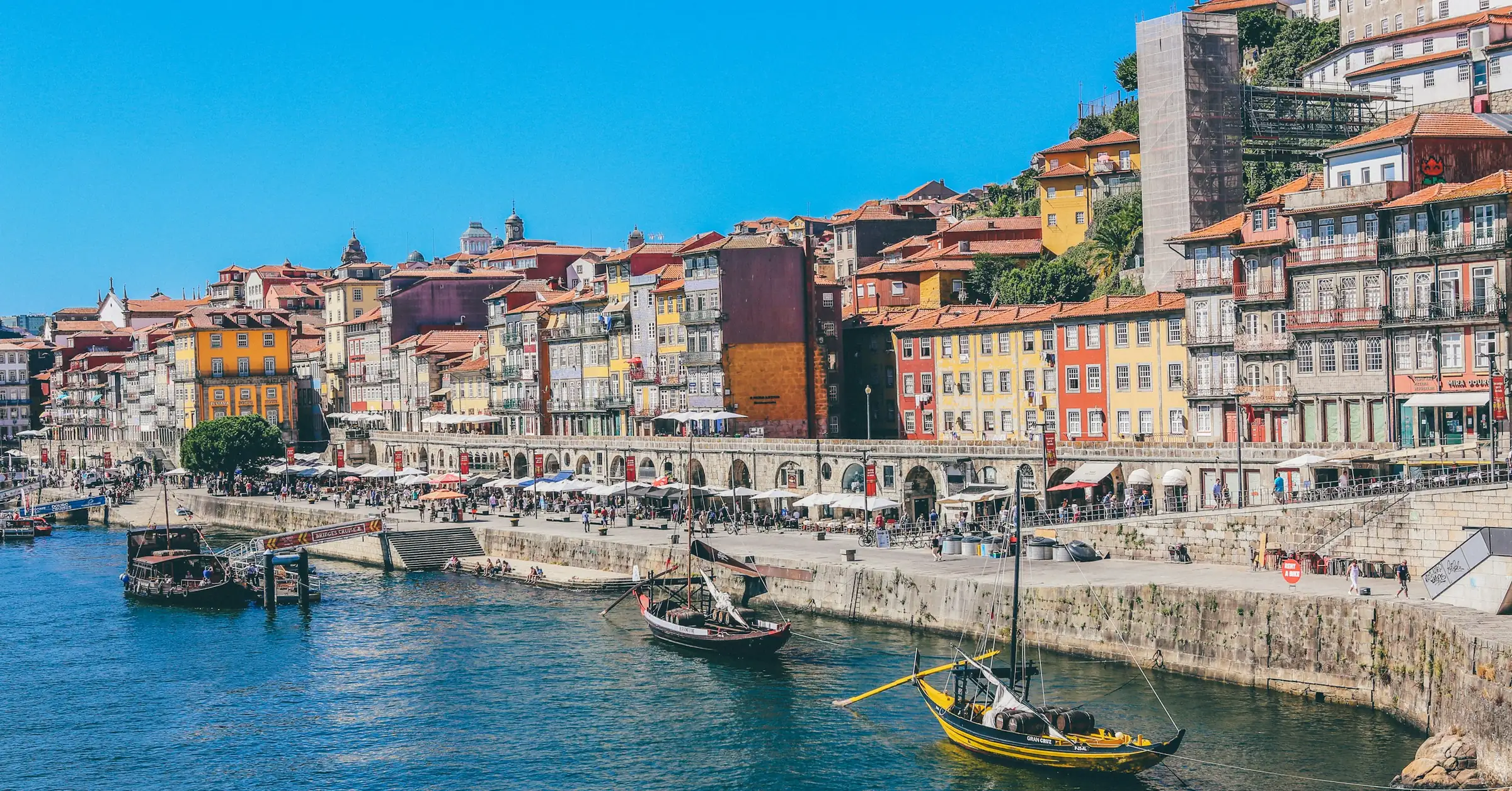 Where to stay in Porto: traditional rabelo boats moored below the colourful houses of the Ribeira waterfront